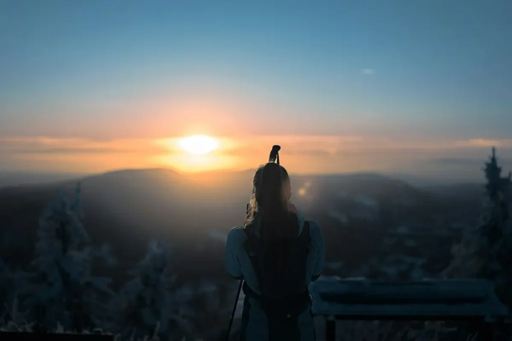 Solo traveler with backpack looking out over a stunning mountain vista